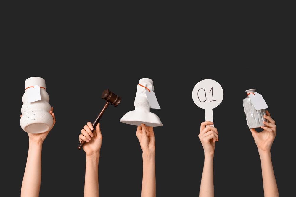 Female,Hands,With,Auction,Paddle,,Gavel,And,Antique,Items,On