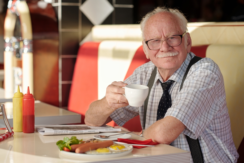 Portrait,Of,Elderly,Man,With,Mustache,Sitting,In,Diner,,Smiling
