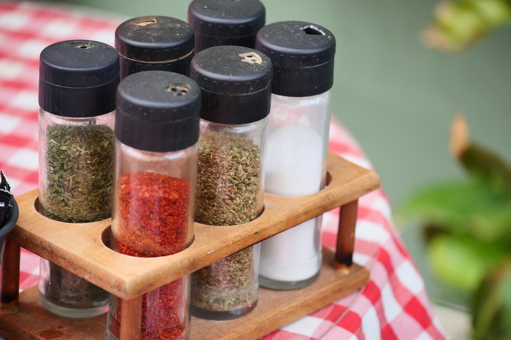 Spice,Jars,On,Wooden,Rack,At,Outdoor,Dining,Table,Setting